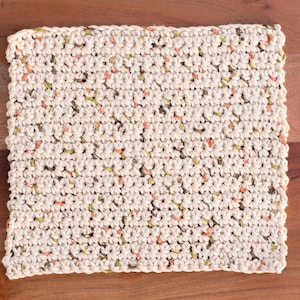 Puede incluir: Primer plano de un pa&ntilde;o de cocina de ganchillo con un patr&oacute;n moteado en tonos beige, verde y naranja.
