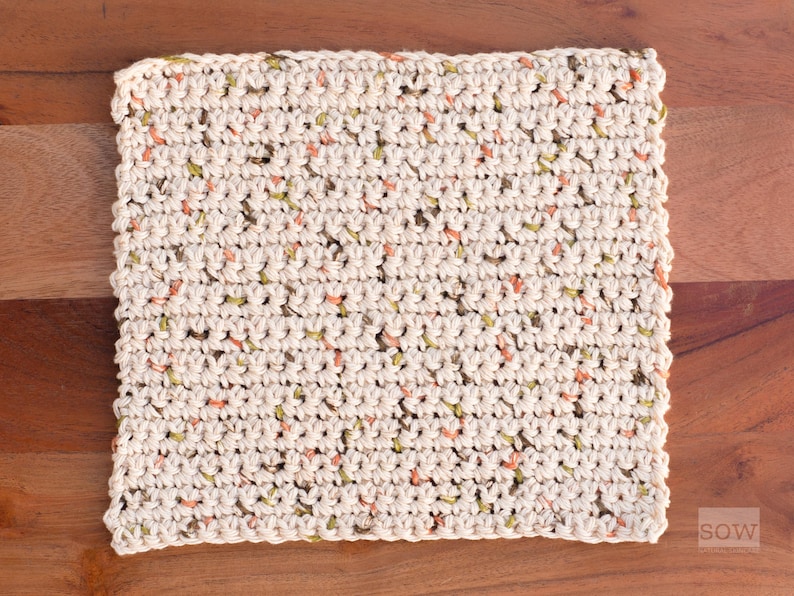 Puede incluir: Primer plano de un pa&ntilde;o de cocina de ganchillo con un patr&oacute;n moteado en tonos beige, verde y naranja.