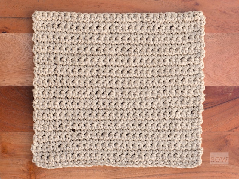 Puede incluir: Un pa&ntilde;o de cocina o toalla de cocina de crochet beige. El pa&ntilde;o est&aacute; hecho con un patr&oacute;n de punto simple y tiene una superficie ligeramente texturizada.