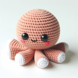 Könnte beinhalten: Handgefertigtes Häkeltier in Form eines Oktopus in einem sanften Pfirsichton. Der Oktopus hat einen runden Kopf, große schwarze Augen, rosige Wangen und einen lächelnden Mund. Die Tentakel sind pfirsichfarben mit weißen Spitzen. Ein niedliches Kuscheltier.