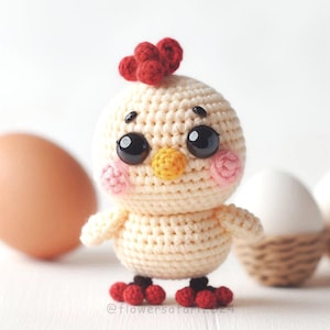 May include: A crocheted chick toy with large black eyes, a yellow beak, and red and white accents. The chick is wearing red roller skates and is standing on a white surface.