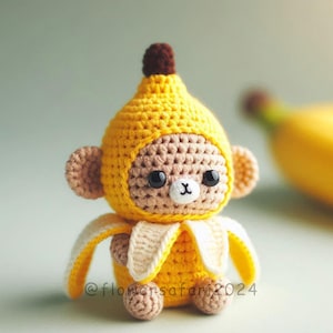 May include: A handmade crochet monkey doll wearing a yellow banana costume. The doll has a brown face, large black eyes, and a white 'X' shaped mouth. The banana peel is white and yellow. The doll is approximately 4 inches tall.