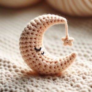 May include: A crocheted crescent moon with a star on top, in a peach color. The moon has embroidered eyes and a smiling mouth.