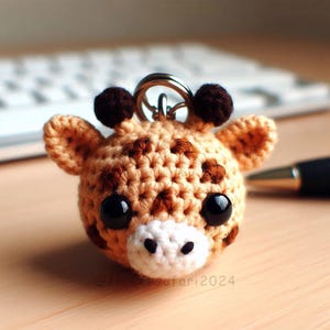 Peut inclure: Un porte-clés en forme de girafe crocheté avec des taches brunes, des yeux noirs et un nez blanc. Le porte-clés est attaché à un anneau en métal argenté.