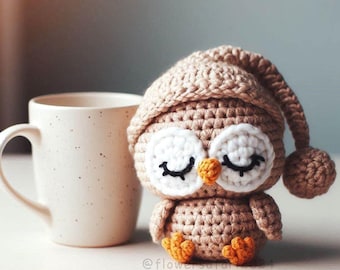 May include: A crocheted owl wearing a crocheted sleeping cap. The owl is brown with white eyes and a yellow beak. The owl is sitting on a white surface.