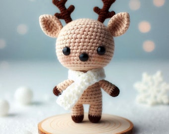 May include: A small crocheted reindeer toy with brown antlers, a white scarf, and black eyes. The reindeer is standing on a wooden base.