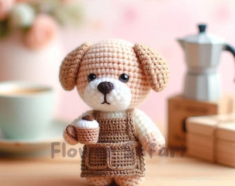 May include: A crocheted dog figurine in a brown apron holds a tiny coffee cup. The dog has tan fur, black eyes, and a white muzzle. The word "Flo" is visible on the bottom left. The background is a soft pink.