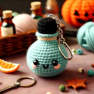 Puede incluir: Una botella de poción azul de crochet con un tapón de corcho negro y una cara sonriente. La botella está unida a un llavero plateado.