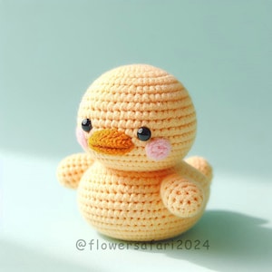 May include: A crocheted yellow duck plush toy with black eyes, an orange beak, and pink cheeks.