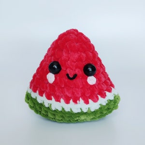 May include: A red and green crocheted watermelon plush toy with a smiling face and black eyes.
