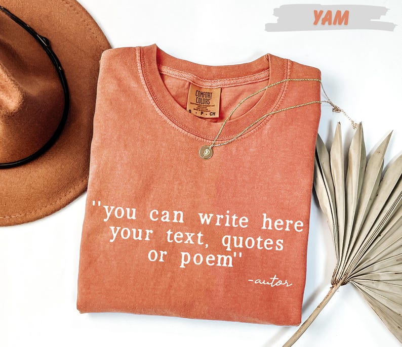 a red t-shirt with a quote printed on it, along with a hat and a fan, all placed on a white background.