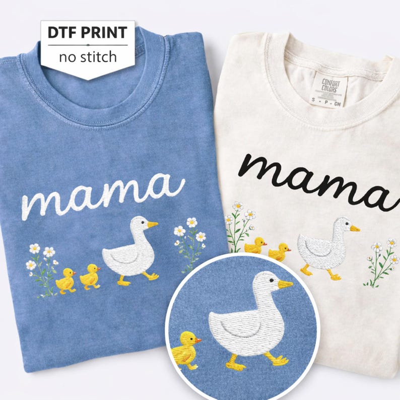 two t-shirts with a mother duck and her ducklings embroidered on them. The t-shirt on the left is blue, and the t-shirt on the right is white.