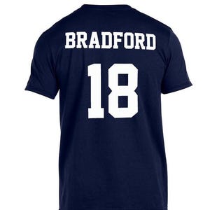 May include: A navy blue t-shirt with white text that reads "BRADFORD 18" on the back.