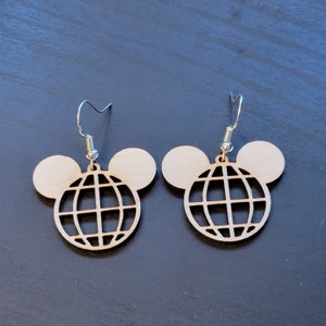 May include: A pair of wooden earrings featuring a Mickey Mouse silhouette and a globe design. The earrings are light brown and have silver hooks.