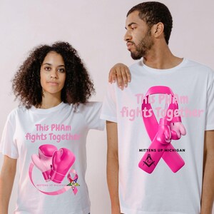 May include: Two people wearing white t-shirts with a pink ribbon and boxing gloves design. The text on the shirts reads "This PHAM fights Together" and "Mittens Up Michigan". The design includes a pink ribbon and a Masonic symbol.