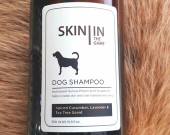 May include: A brown bottle of dog shampoo with a black cap. The label reads "SKIN IN THE GAME DOG SHAMPOO" with a dog silhouette. It contains 16.9 fl.oz. of Spiced Cucumber, Lavender & Tea Tree Scent shampoo.