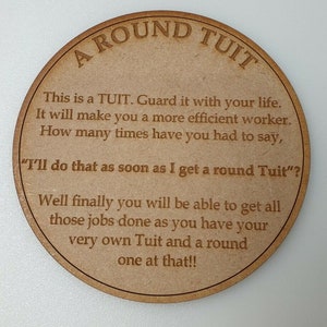 May include: A round wooden disc with the words "A ROUND TUIT" engraved at the top. The disc contains a humorous message about productivity, including the phrase "I'll do that as soon as I get a round Tuit?"