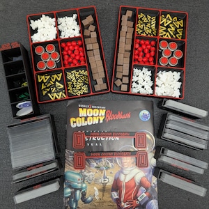 Peut inclure: Jeu de société "Moon Colony Bloodbath" avec des pièces dans des plateaux rouges et noirs. Le jeu comprend des cartes, des jetons et un manuel avec une illustration de science-fiction d'astronautes et de robots.