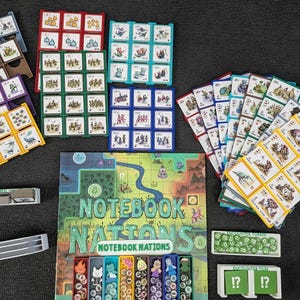 Pode incluir: Um jogo de tabuleiro intitulado Notebook Nations com um mapa colorido, vários tabuleiros de grelha em vermelho, verde, azul e amarelo, pilhas de cartas ilustradas, fichas circulares verdes e vários tabuleiros de plástico com peças.
