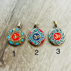 May include: Three round pendants with a gold frame and a blue and red mosaic design. The center of each pendant features a gold Om symbol.