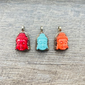 May include: Three silver pendants with Buddha faces. The pendants are in red, blue, and orange.