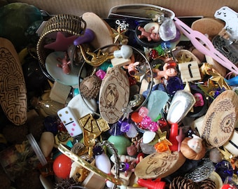 May include: A box overflowing with a variety of trinkets and small objects, including wooden carvings, glass beads, metal charms, and a domino. The objects are arranged in a chaotic and colorful manner, creating a visually stimulating scene.