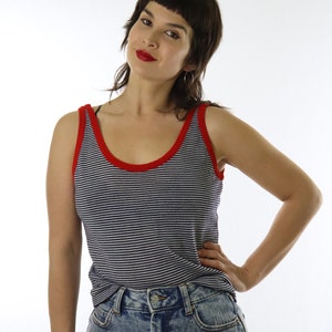 May include: A navy and white striped vest top with red edging. The top is worn with a light wash denim skirt. The model is wearing the vest top and skirt.