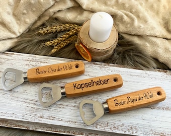 May include: Three wooden bottle openers with engraved messages. The first opener says "Best Opa in the World", the second says "Kapselheber", and the third says "Best Papa in the World".