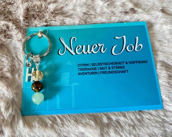 May include: A silver key chain with a charm that says "H" and has three gemstone beads. The key chain is displayed on a blue card with the text "Neuer Job" and a list of gemstones and their meanings.