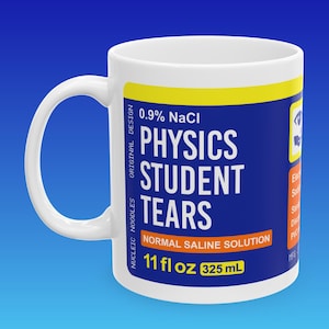 May include: White ceramic mug with a blue and yellow label that reads "0.9% NaCl Physics Student Tears Normal Saline Solution 11 fl oz 325 mL".