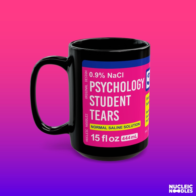 May include: Black ceramic mug with a pink and blue label that reads "0.9% NaCl Psychology Student Tears Normal Saline Solution 15 fl oz 444 ml".