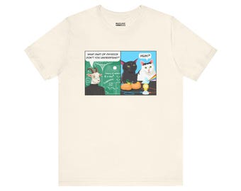 Puede incluir: Camiseta color crema con diseño de cómic. El panel izquierdo muestra una cabra y el texto: "¿QUÉ PARTE DE LA FÍSICA NO ENTIENDES?" El panel derecho muestra dos gatos y la palabra "¿EH?" La camiseta es de la marca "NUCLEIC NOODLES".