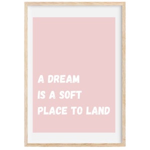 May include: A pink framed print with the text "A dream is a soft place to land" in white.