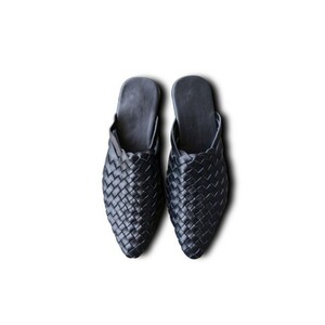 May include: A pair of black woven leather slippers with a pointed toe.