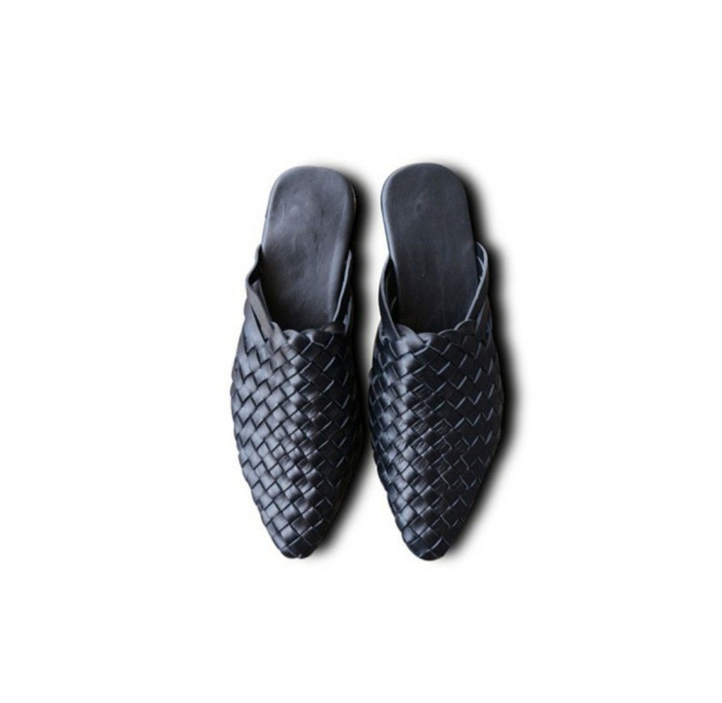 May include: A pair of black woven leather slippers with a pointed toe.