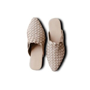 May include: A pair of beige woven leather mules with a pointed toe.