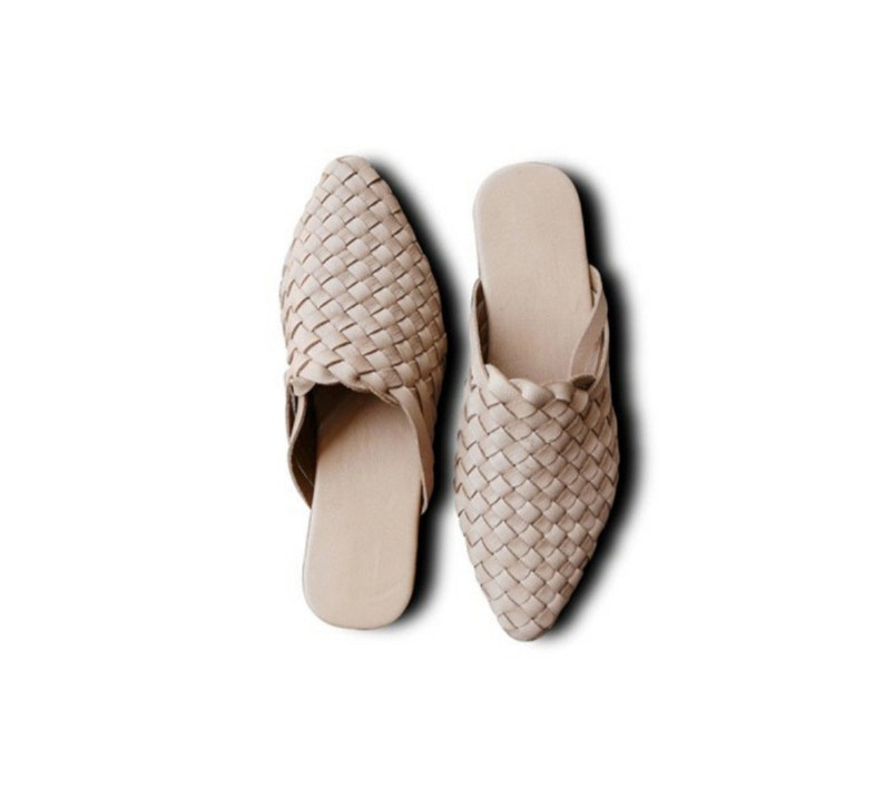 May include: A pair of beige woven leather mules with a pointed toe.