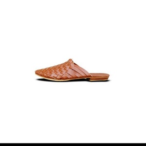 May include: A pair of brown leather woven slip-on shoes with a pointed toe.