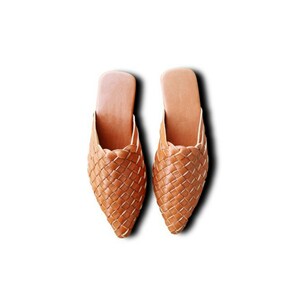 May include: A pair of brown leather woven slippers with a pointed toe.