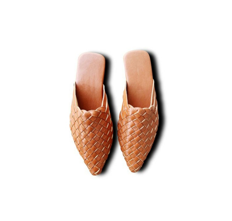 May include: A pair of brown leather woven slippers with a pointed toe.