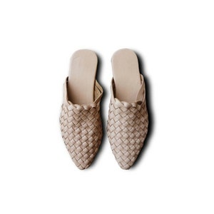 May include: A pair of beige woven leather mules with a pointed toe.