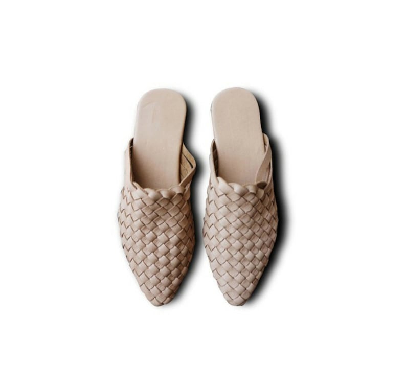 May include: A pair of beige woven leather mules with a pointed toe.