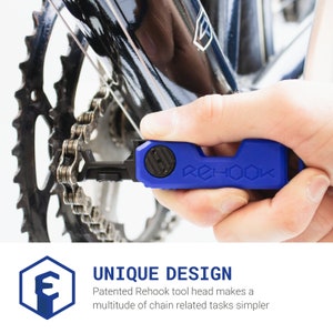 Pode incluir: Uma ferramenta de corrente de bicicleta azul com o texto "REHOOK" impresso nela. A ferramenta est&aacute; sendo usada para reparar uma corrente de bicicleta.