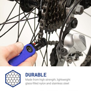 Pode incluir: Uma ferramenta de corrente de bicicleta azul com uma pega preta. A ferramenta est&aacute; sendo usada para remover um elo de uma corrente de bicicleta. A corrente est&aacute; presa a um desviador traseiro de bicicleta.