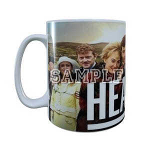 Pode incluir: Caneca de cerâmica branca com um grupo de pessoas e a palavra "HEART" em letras brancas grandes. A caneca tem uma alça branca e um fundo cênico.