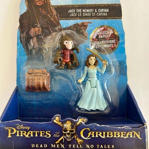 May include: A packaged Disney Pirates of the Caribbean toy set featuring Jack the Monkey, Carina, and a treasure chest. The packaging includes the text "Dead Men Tell No Tales" and "Collect & Battle!"