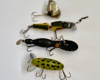 Può includere: Quattro esche da pesca con colori e design diversi. Le esche sono realizzate in metallo e plastica e hanno ami. Le esche sono su uno sfondo bianco.