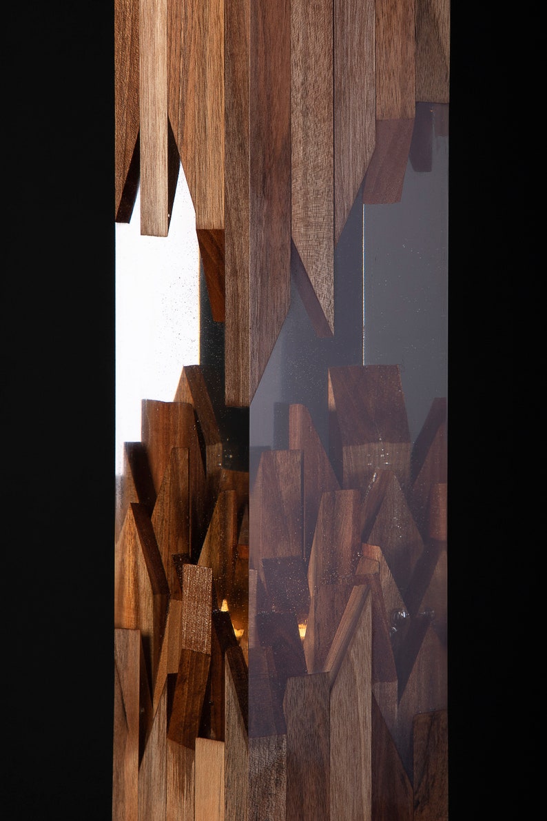 May include: A tall, rectangular sculpture made of wood and clear resin. The wood is arranged in a geometric pattern, creating a unique and modern design. The resin is clear and allows the wood to be seen through it.