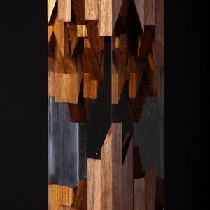 May include: A tall, clear resin sculpture with a geometric pattern of brown wood pieces embedded inside. The wood pieces are arranged in a random pattern, creating a unique and modern design.