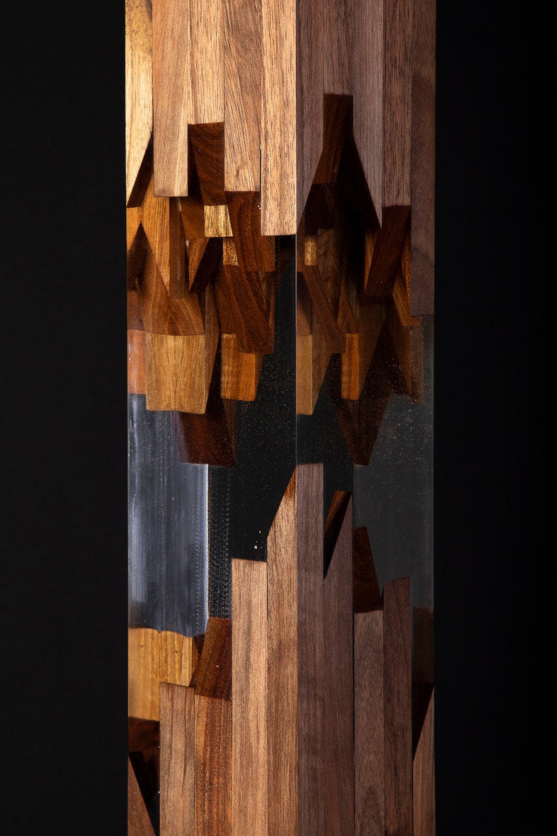May include: A tall, clear resin sculpture with a geometric pattern of brown wood pieces embedded inside. The wood pieces are arranged in a random pattern, creating a unique and modern design.